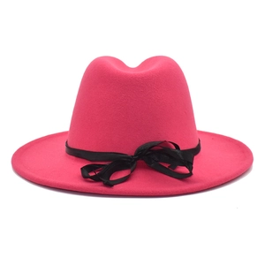 Détail du chapeau fedora rose fuchsia avec un ruban de satin noir et un nœud latéral