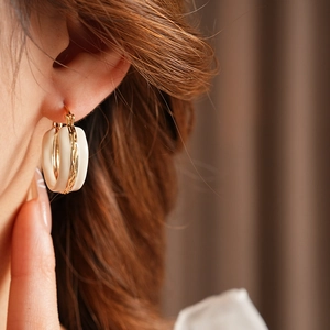 Modella che indossa orecchini a cerchio vintage geometrici in oro e smalto beige