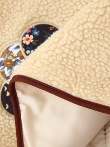 Close-up of beige fleece vest featuring brown trim and high-quality lining texture
