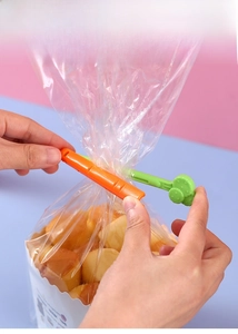 Démonstration manuelle de clips en plastique en forme de carotte scellant un sac de snack