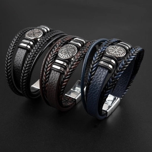 Detail view of multi-layer leather bracelets in black, brown, and blue with tree of life charm