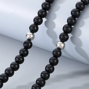 Detailed macro shot of black onyx beads and silver accents on a minimalist necklace