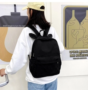 Detail of cute rabbit ear design on black canvas backpack shown on model for daily use