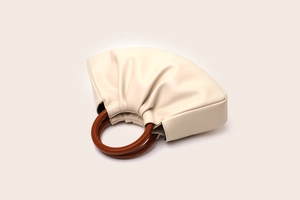Close-up of pleated PU leather bag featuring unique round wooden handle in beige