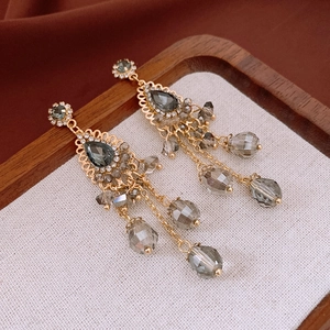Detailed close-up of vintage golden tassel earrings with dark grey crystals and rhinestones