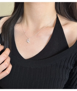 Close-up of S925 silver star necklace with pink zircon on model neck against black top
