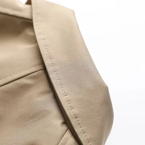 Detailaufnahme der präzisen Nähte und des hochwertigen Twill-Stoffs am khakifarbenen Trenchcoat