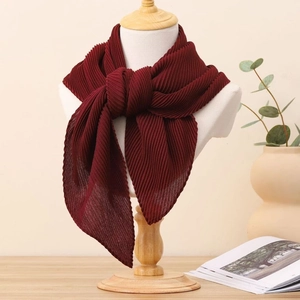 Gros plan d'un foulard carré plissé bordeaux en coton et lin sur un mannequin en bois