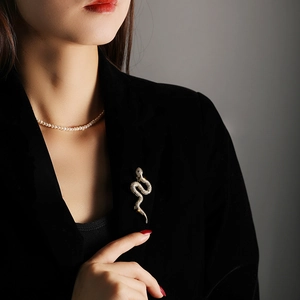 Detail shot of a copper snake brooch with cubic zirconia on a black blazer lapel