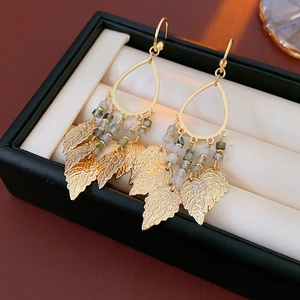 Vue macro de boucles d'oreilles feuilles dorées avec perles dans un écrin à bijoux
