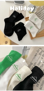 Close-up of dreamer logo embroidery on cotton ribbed crew socks in black white and green