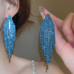 Détail de boucles d'oreilles longues en aiguille d'argent avec strass bleus et franges