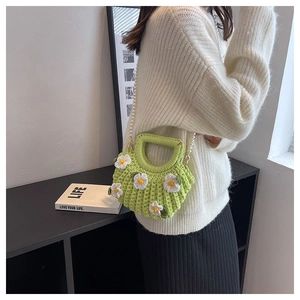 Detail of light green hand-woven shell bag with white daisies and pearl strap