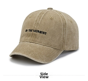Close-up of khaki washed cotton baseball cap featuring IN THE MOMENT black embroidery