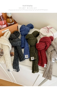 Close-up of chunky knit scarves in various colors with minimalist logo labels