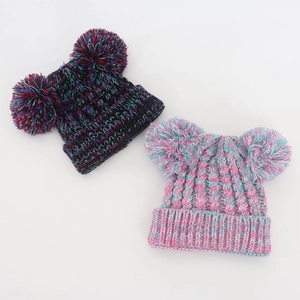 Detailed close-up of mixed color knit baby beanie with double faux fur pom-poms