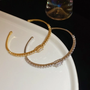 Macro shot of gold and silver plated bangles with zircons on a white ceramic plate