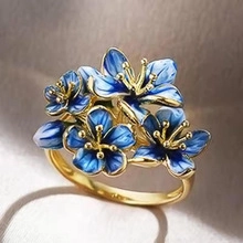 Macro detail of a gold ring featuring blue enamel flower petals and a yellow stamen center