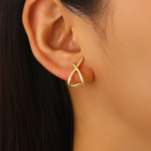 Close-up of elegant gold X-shaped crisscross earrings worn on a female model