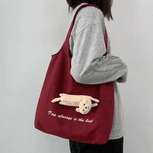 Detail view of burgundy canvas shoulder bag with cute plush cat and letter printing