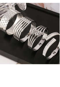 Detail of four silver titanium steel bracelets with hollow patterns and zircon inlay design