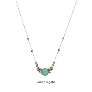 Detailed close-up of green agate bead pendant with golden rings on stainless steel chain
