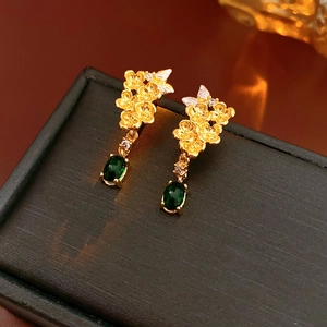 Détail de boucles d'oreilles fleur vintage avec pierres vertes sur boîte à bijoux noire