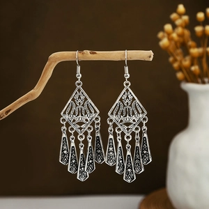 Detailed view of vintage silver tassel earrings hanging on a natural wooden branch