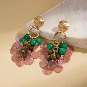 Detail of bohemian drop earrings with gold metal, green beads and purple shell discs