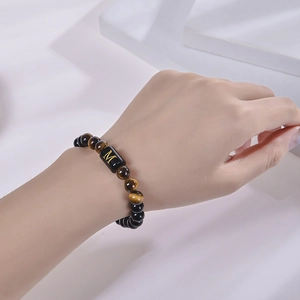 Bracelet en œil de tigre et obsidienne avec lettre M dorée porté au poignet