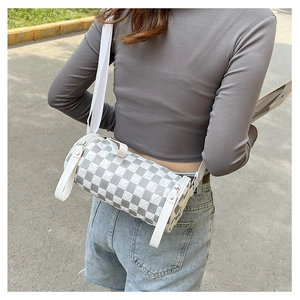 Detail view of the cylinder crossbody bag featuring grey checkerboard pattern and wide strap