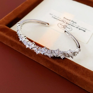 Vue macro d'un bracelet ouvert irrégulier pavé de zircons dans son écrin de velours