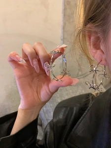Detail of silver bow hoop earrings worn by a model, showing large delicate metal rings