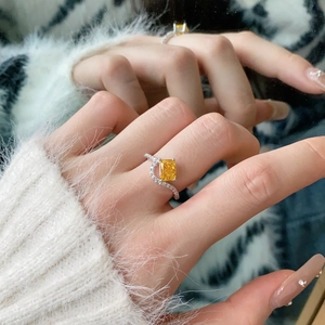 Close-up of yellow radiant cut gemstone ring with wavy diamond pave band on hand