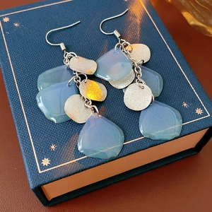 Dettaglio di orecchini con paillettes blu e dischi d'argento su una scatola regalo