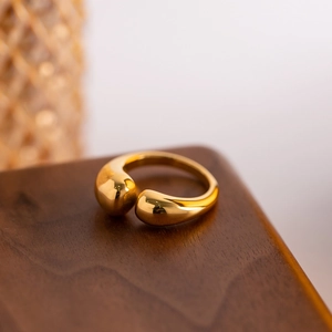 Macro detail of polished gold teardrop ring on a premium wood surface with mirror finish