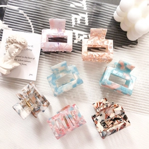 Artistic arrangement of acetate dog and cat hair clips on white marble background