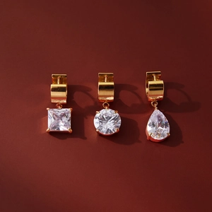 Trois boucles d'oreilles huggie dorées avec des zircons carrés, ronds et en poire