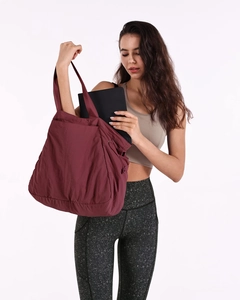 Deep red waterproof tote bag showing interior space and laptop storage capacity