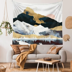 Artistic tapestry with navy and gold mountains hanging over a modern sofa in a warm room