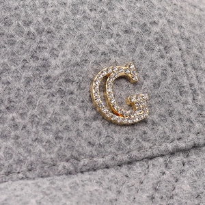 Macro view of crystal-encrusted gold logo on grey corduroy baseball cap texture