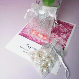 Close-up of white organza gift bag with silver bow ribbon and drawstring closure