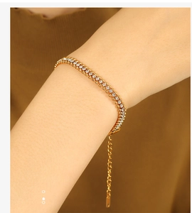 Detail shot of a gold-plated tennis bracelet with double-row crystals on a female wrist
