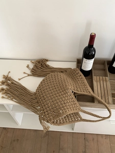 Scatto dettagliato della borsa con frange intrecciata a mano boho per la vacanza al mare.