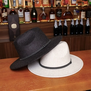 Two-tone wool fedora hats in black and beige with studded bands on a wooden bar counter