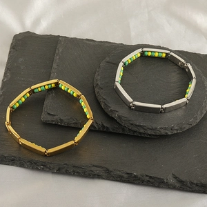 Titanium steel beaded bracelets in gold and silver finish on a dark stone background