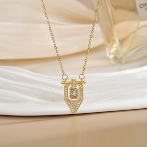 Close-up of gold titanium necklace with a rectangular gemstone pendant and micro-pavé diamonds