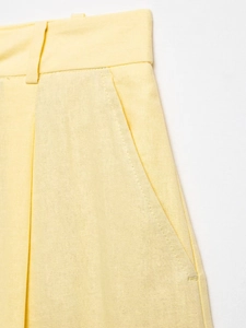 Close-up of light yellow cotton-linen fabric showing pocket detail and stitching quality