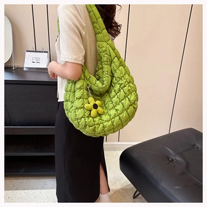 Detailed view of green quilted puffer tote bag with floral charm and square stitching
