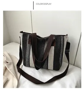 Close-up of black and white striped canvas tote bag with brown straps and metal buckle